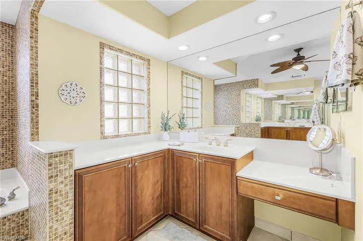Expansive vanity with a light-toned countertop, wood-finish cabinetry, and an integrated makeup desk