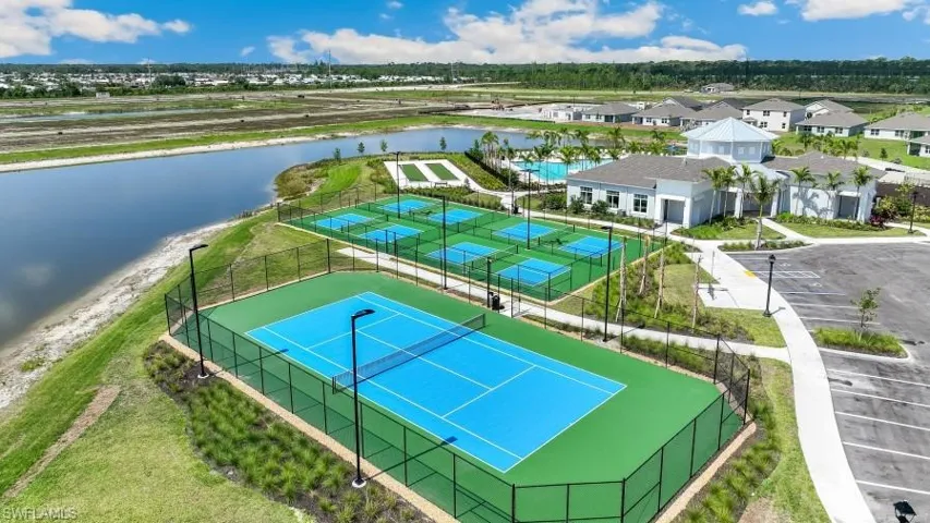 The property features a tennis court, multiple pickleball courts, and a community building, all set alongside a body of water