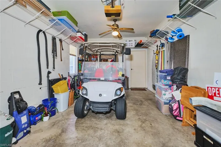 Garage featuring concrete block wall, a garage door opener, and a ceiling fan