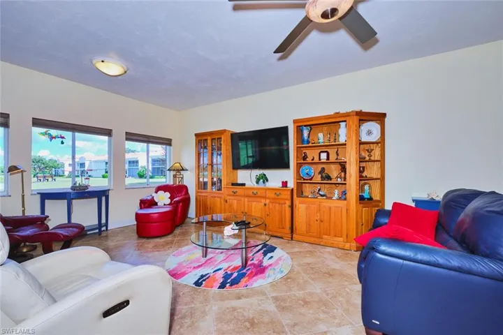 Living area featuring light tile patterned floors and a ceiling fan