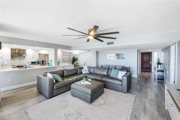 Living room featuring light wood-style flooring, ceiling fan, recessed lighting, and a chandelier