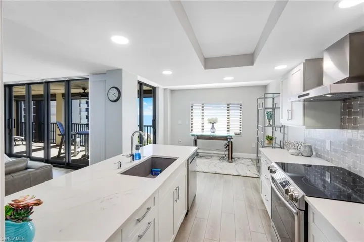 Kitchen featuring appliances with stainless steel finishes, white cabinetry, wall chimney exhaust hood, decorative backsplash, and recessed lighting