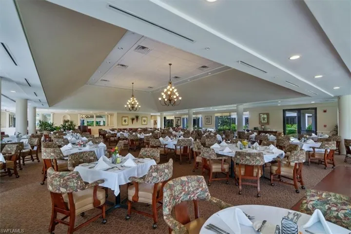 Carpeted dining area with a tray ceiling and an inviting chandelier
