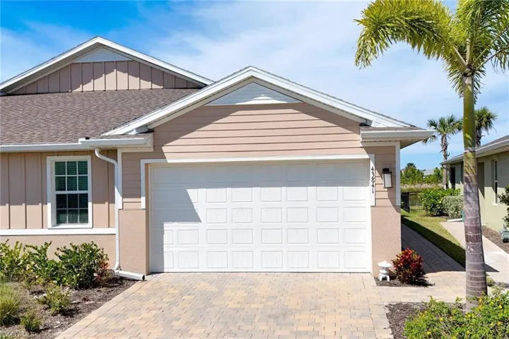 Villa with attached 2 car garage, board and batten siding & pavered driveway
