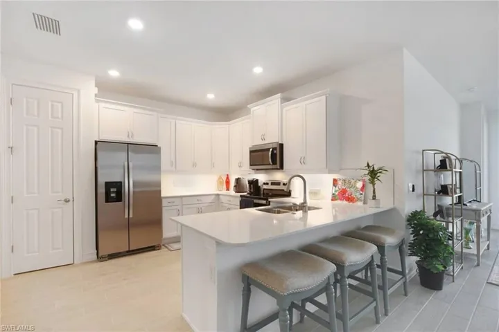 Open Kitchen featuring dining bar/peninsula, soft close white cabinetry & stainless steel appliances