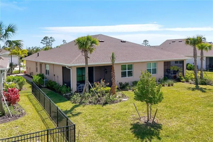 Back of property with a yard, roof with shingles, fence, and stucco siding