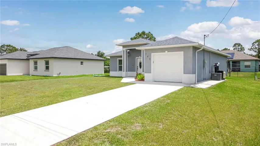 Single-story residence featuring a gray exterior finish, a white garage door, and a concrete driveway