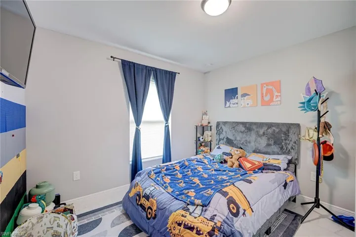 Bright secondary bedroom featuring a large window with blue curtain panels, neutral wall finishes, and recessed ceiling lighting