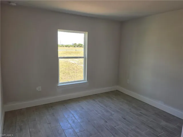 Room featuring wood-look tile flooring, neutral wall tones, white trim, and a double-hung window