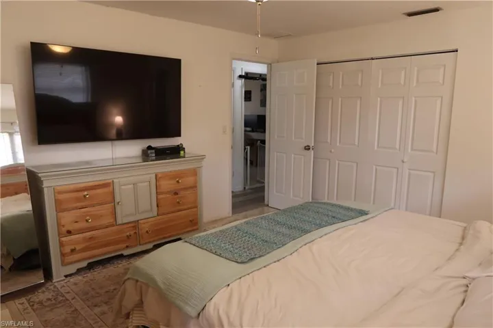 Spacious room featuring a large wall-mounted screen, a built-in closet with bi-fold doors, and a paneled interior door