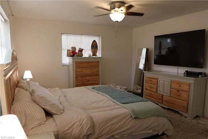 Bedroom featuring overhead ceiling fan with integrated lighting, multiple windows with blinds, and light-toned walls