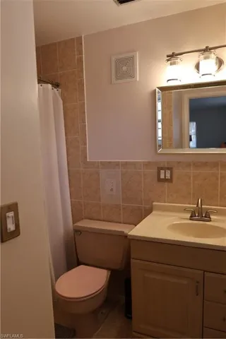 Bathroom vanity with a cream-toned countertop, undermount sink, and brushed nickel faucet