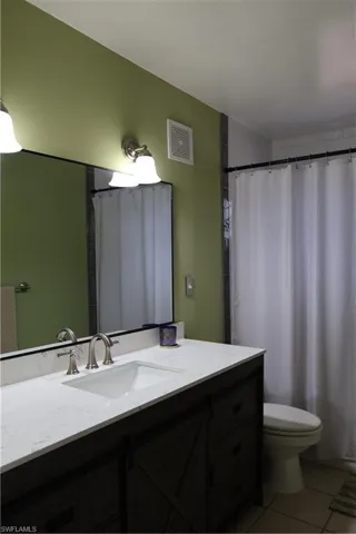 Bathroom featuring a dark wood-finish vanity with a white countertop and undermount sink, brushed nickel faucet, and a wall-mounted mirror