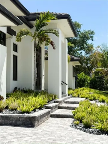 Contemporary exterior with a prominent entry, dual dark-framed glass doors, and a paver walkway