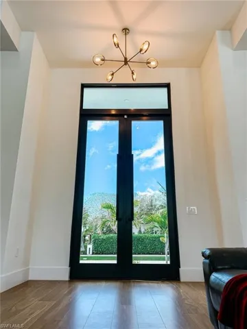 Double-height entry featuring French doors, wood-finish flooring, and lighting fixture