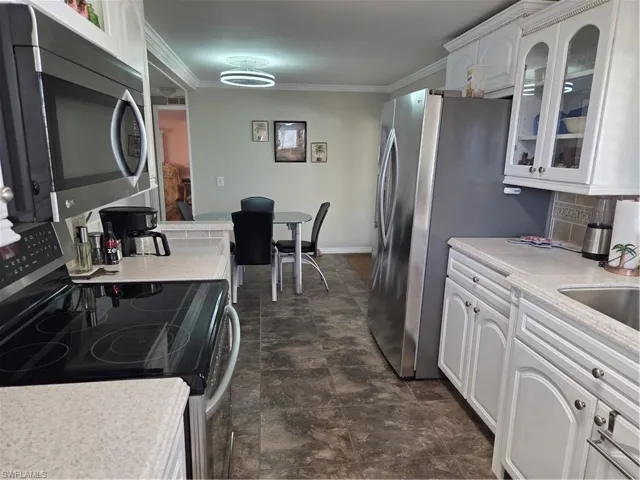 Beautifully remodeled kitchen features a disposal, Corian counters, double sinks, and stainless steel appliances including DW & double-door refrigerator with ice.