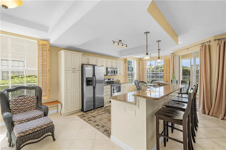 Kitchen with cream cabinets, a breakfast bar, appliances with stainless steel finishes, and light tile patterned floors