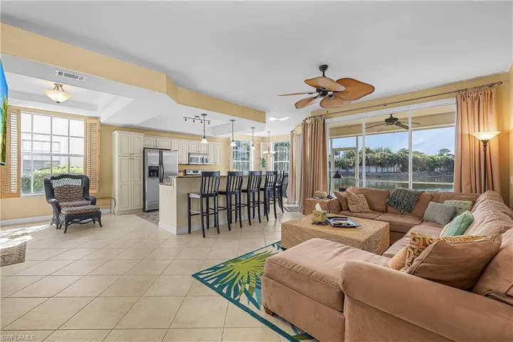 Living room with a water view, plenty of natural light, light tile patterned floors, and a ceiling fan