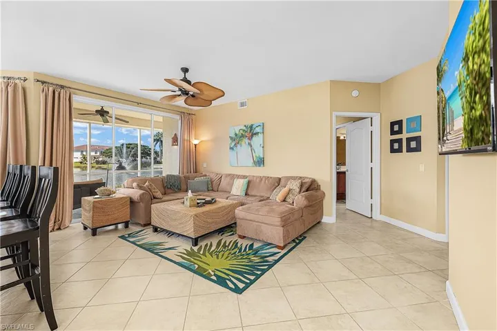Living room with light tile patterned flooring, a water view, and ceiling fan
