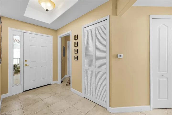 Entrance foyer featuring light tile patterned floors and a raised ceiling