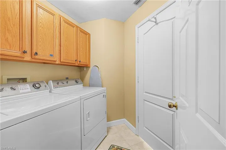 Washroom with washer and clothes dryer, cabinet space, and light tile patterned flooring