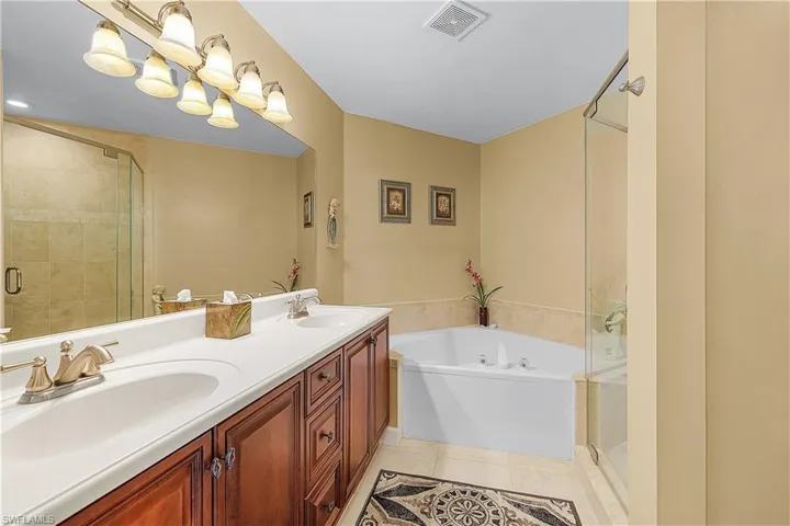 Full bath featuring a stall shower, a bath, double vanity, and light tile patterned floors