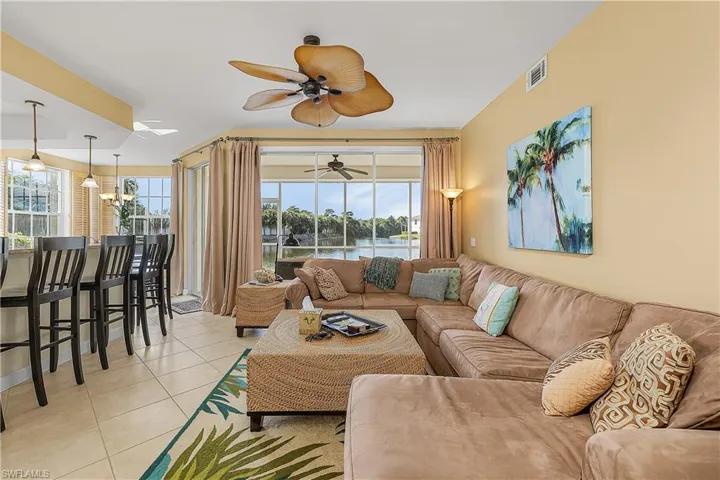 Living area with light tile patterned flooring, a water view, and ceiling fan