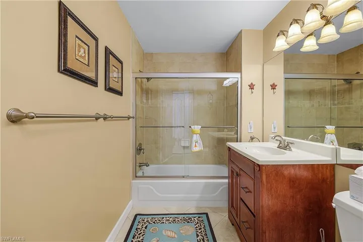 Full bathroom featuring light tile patterned flooring, shower / bath combination with glass door, and vanity