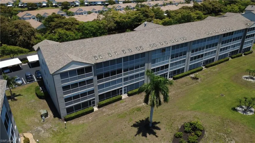 Multi-story building featuring screened balconies, a shingle roof, and exterior landscaping