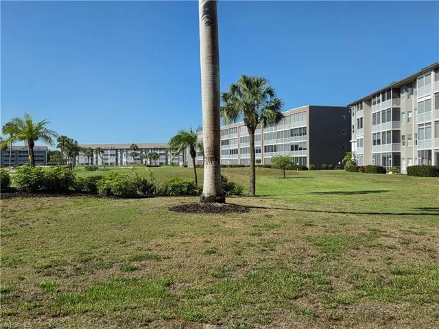Expansive green space featuring mature palm trees and low-rise residential buildings with multiple balconies