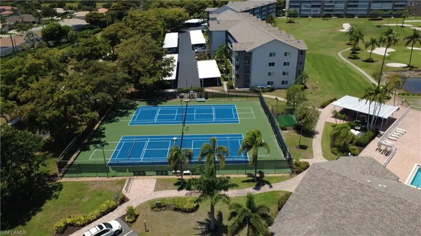Two tennis courts with blue playing surfaces and green surrounds