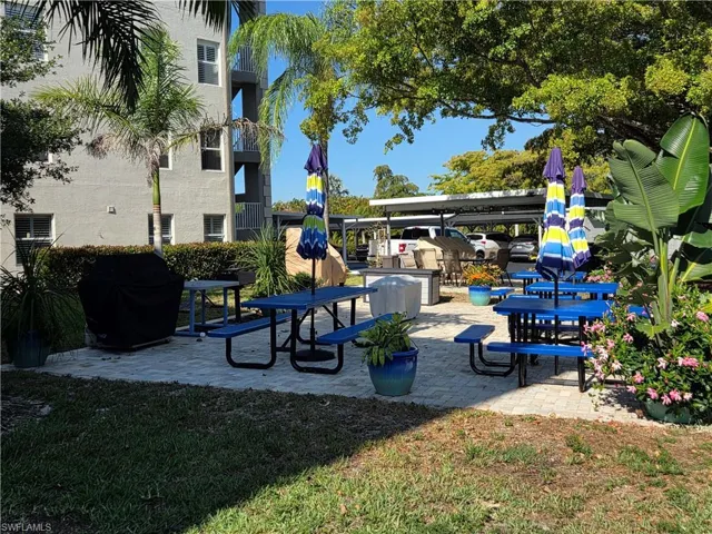 Outdoor amenity area featuring a paver patio with multiple picnic tables and umbrellas