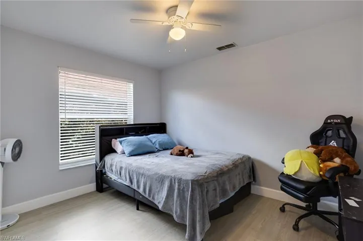 Bedroom featuring a window with blinds, wood-finish flooring, and a ceiling fan with integrated lighting