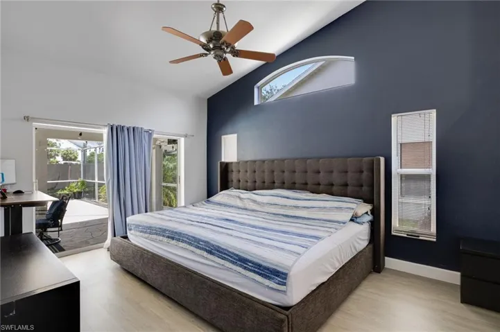Room featuring vaulted ceilings, wood-finish flooring, and a ceiling fan with integrated lighting