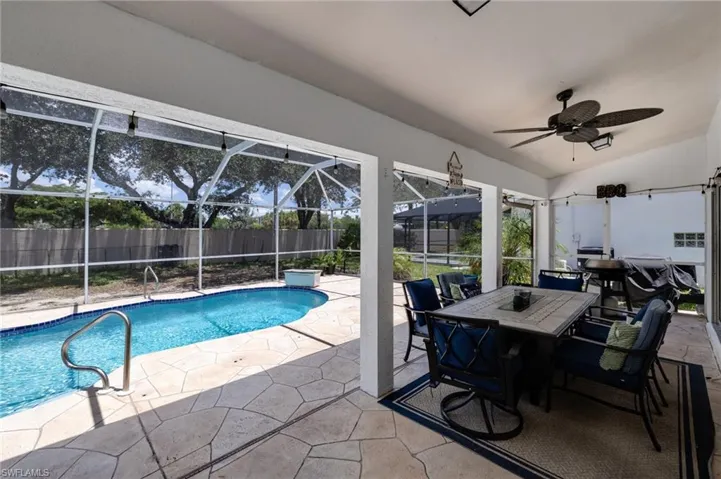 Screened patio featuring a swimming pool with a tiled edge and metal handrails