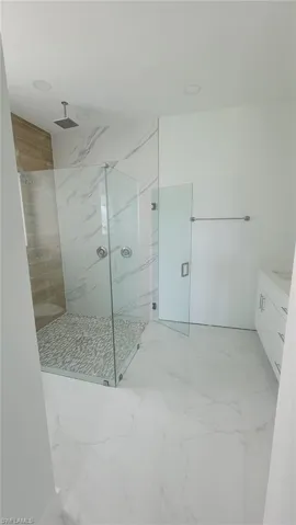 Bathroom with tile patterned flooring, tiled shower, and vanity