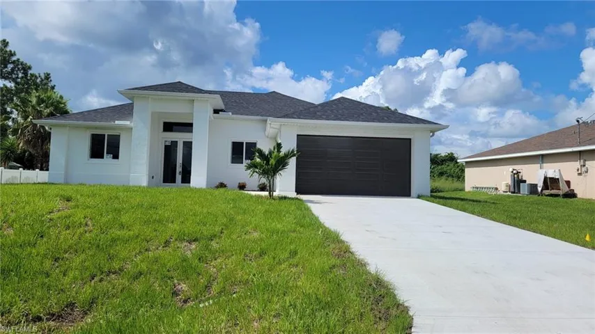 View of front facade featuring a garage and a front lawn