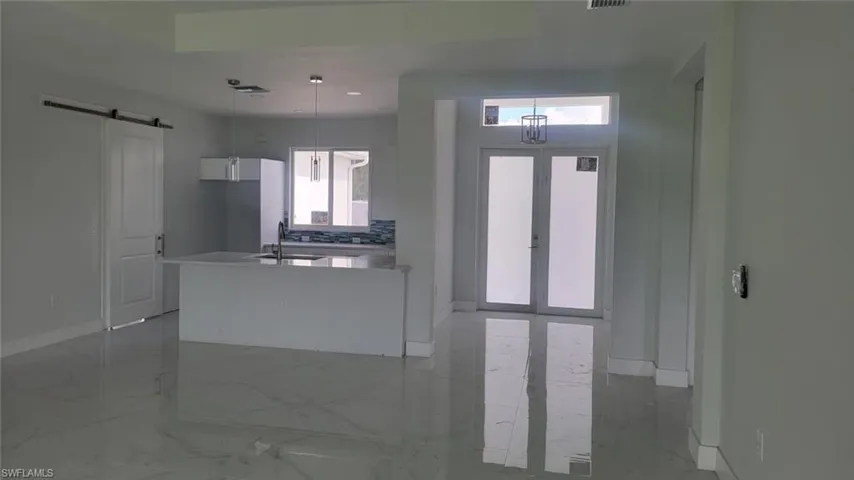 Kitchen featuring decorative light fixtures, light tile patterned flooring, white cabinets, and sink
