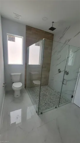 Bathroom with tile patterned flooring, toilet, and tiled shower