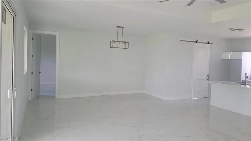Spare room featuring tile patterned flooring, a barn door, sink, and ceiling fan