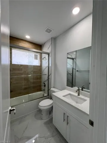 Full bathroom featuring vanity, tile patterned floors, shower / bath combination with glass door, and toilet