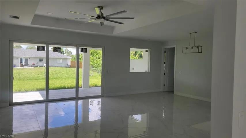 Unfurnished room with plenty of natural light, ceiling fan, tile patterned flooring, and a tray ceiling