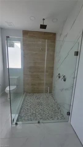 Bathroom with tile patterned floors, walk in shower, and toilet