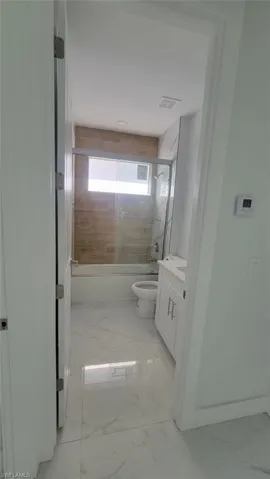 Full bathroom featuring tile patterned flooring, toilet, enclosed tub / shower combo, and vanity