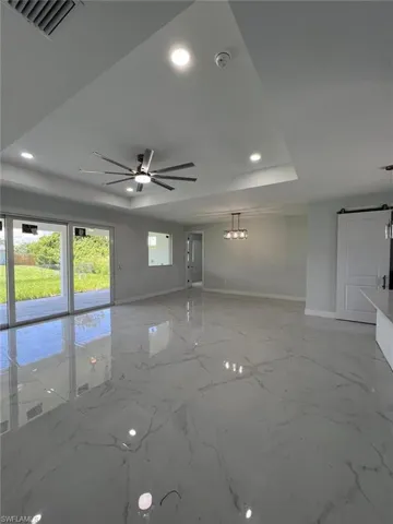 Unfurnished room with ceiling fan, a raised ceiling, and light tile patterned floors