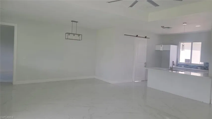 Spare room featuring sink, light tile patterned floors, ceiling fan, and a barn door