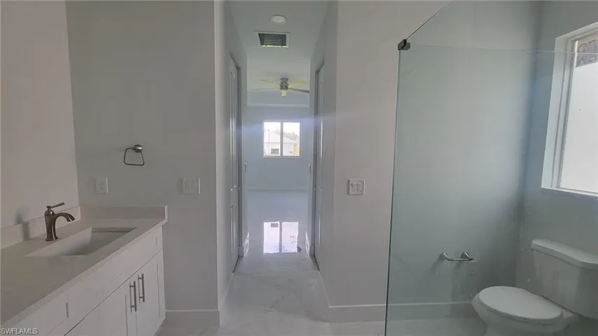 Bathroom with tile patterned floors, toilet, vanity, and ceiling fan