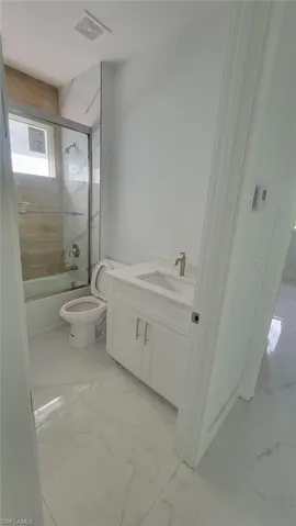 Full bathroom with vanity, tile patterned flooring, shower / bath combination with glass door, and toilet