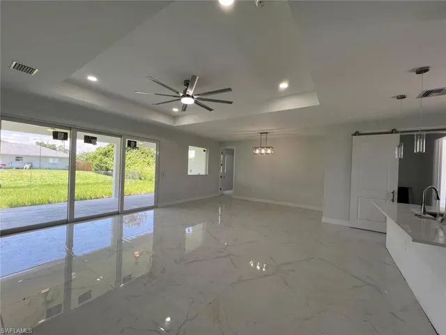 Spare room with tile patterned floors, a raised ceiling, sink, and ceiling fan