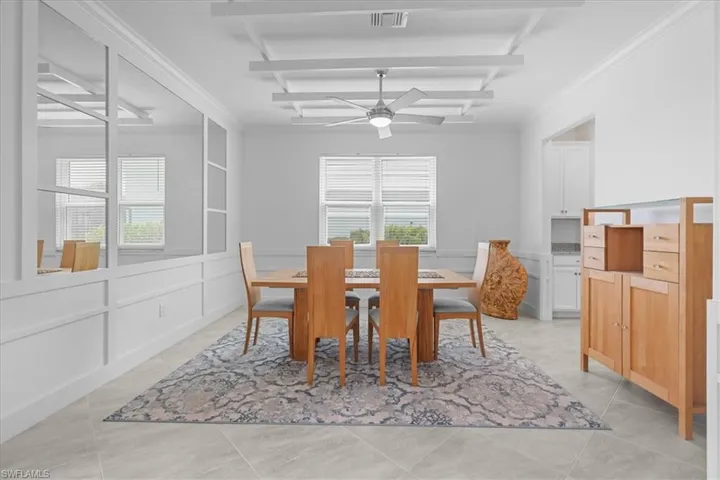 Dining area with a decorative wall, wainscoting, crown molding, and a ceiling fan
